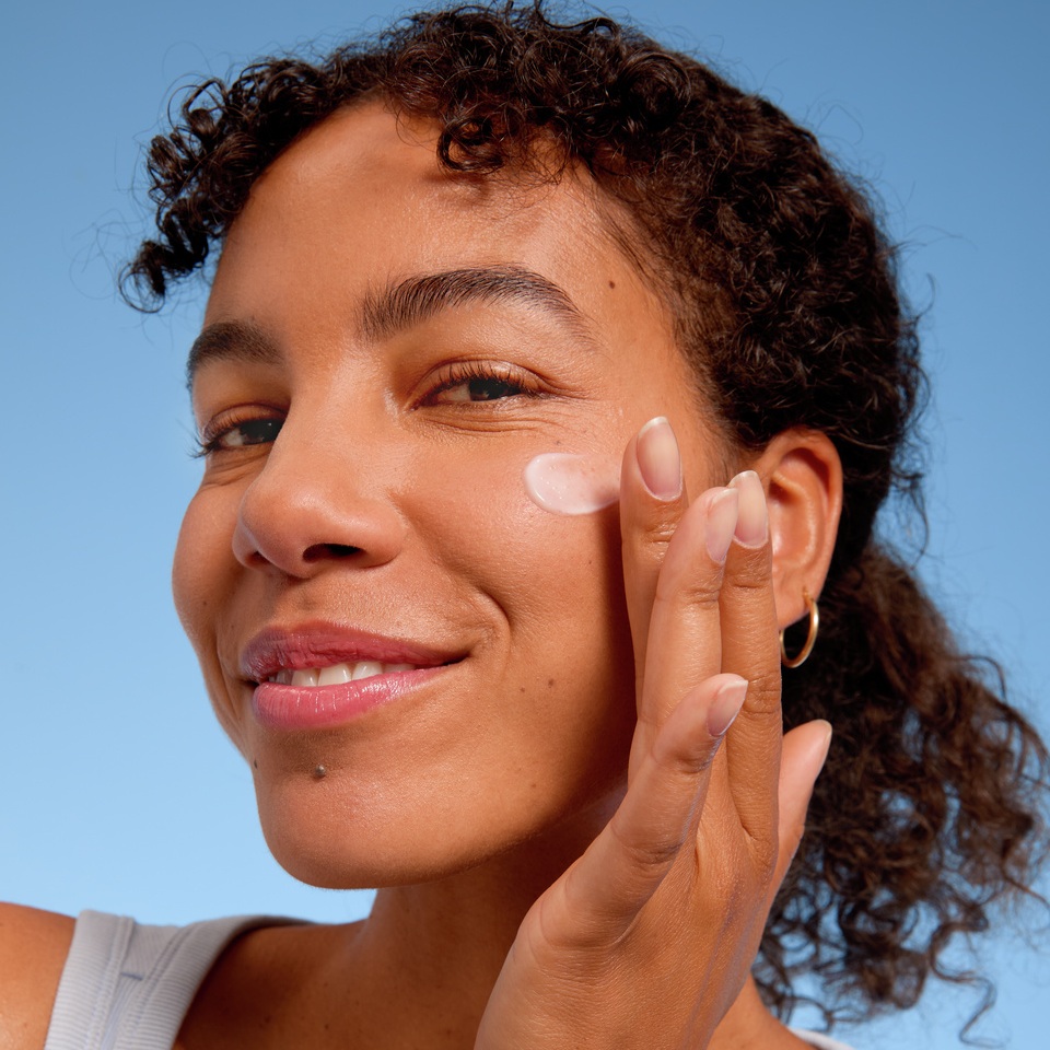 Young woman applying face cream