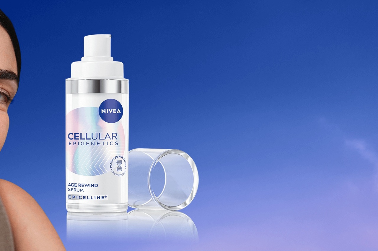 Suoraan katsova nainen vieressään NIVEA CELLULAR Age Rewind Serum -seerumipullo.