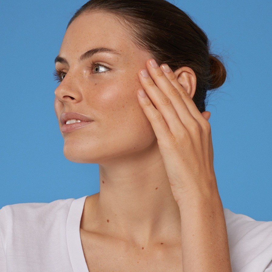 Woman with clear and healthy skin touching her face