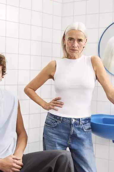 young man and a lady sitting in the bathroom looking to the camera
