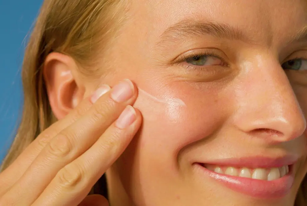 Woman applying the NIVEA 2in1 Primer Daily UV Serum SPF 50+ on her face for smooth skin