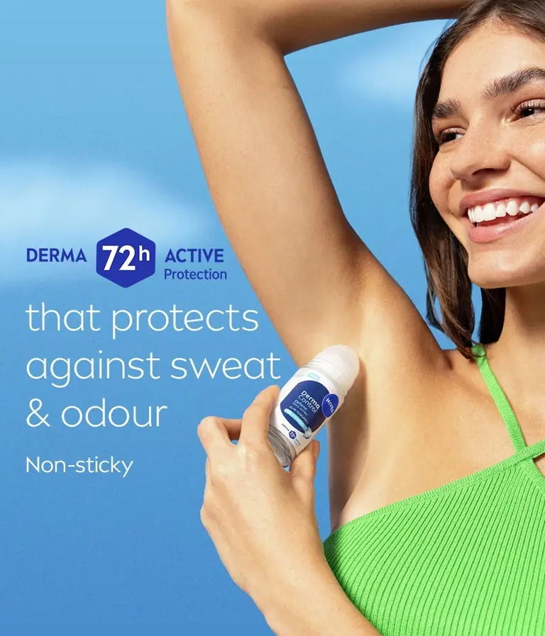 A young woman looks off and smiles while lifting her arm and applying NIVEA Derma Control Defend Deo Roll-On.