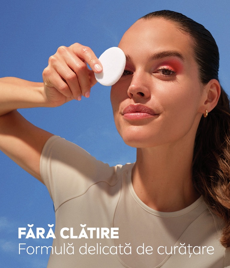 A woman leans back and gazes, holding the Derma Skin Clear Serum-infused Micellar Water under her chin.