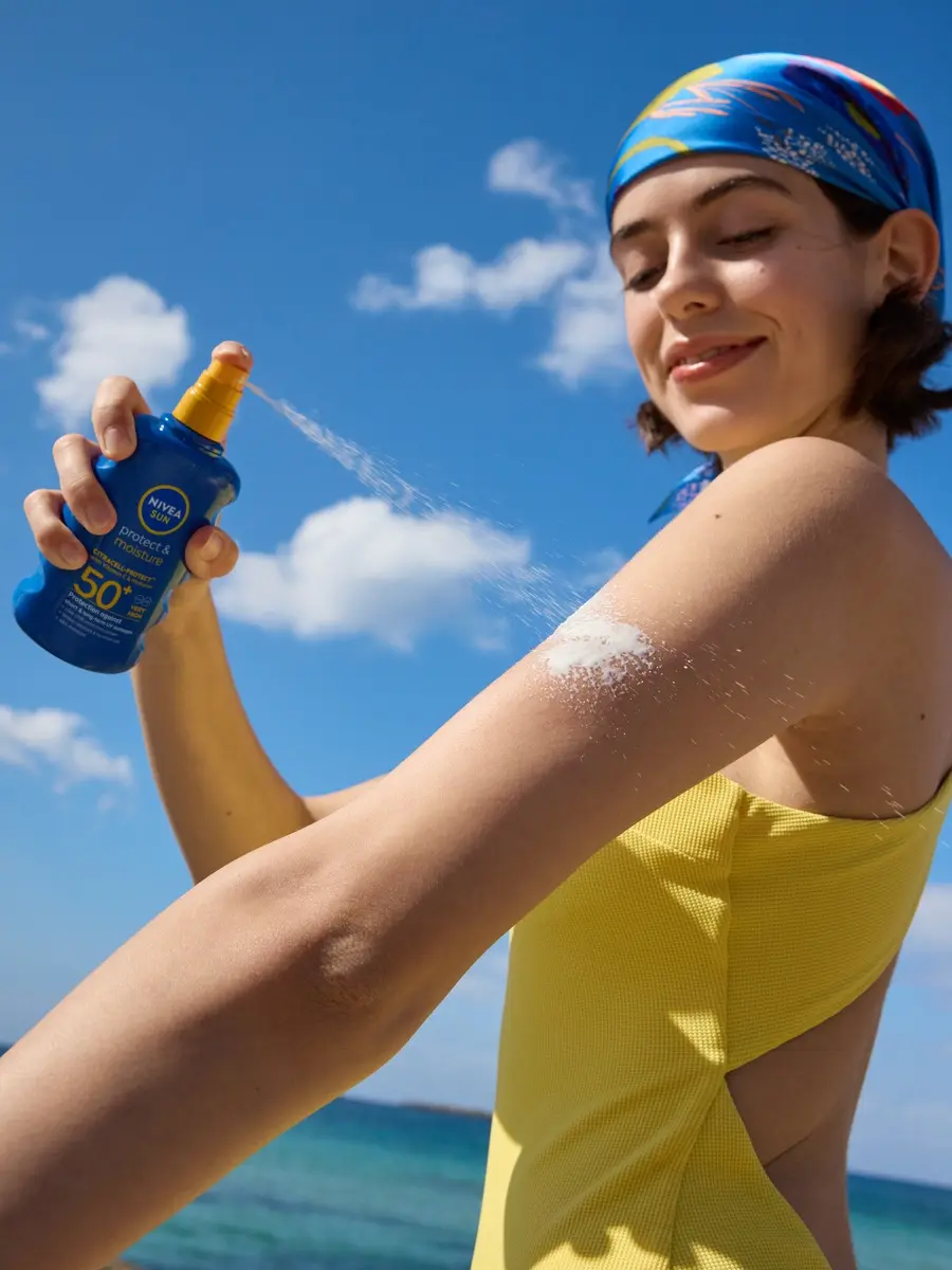 young girl applying Nivea Sun spray