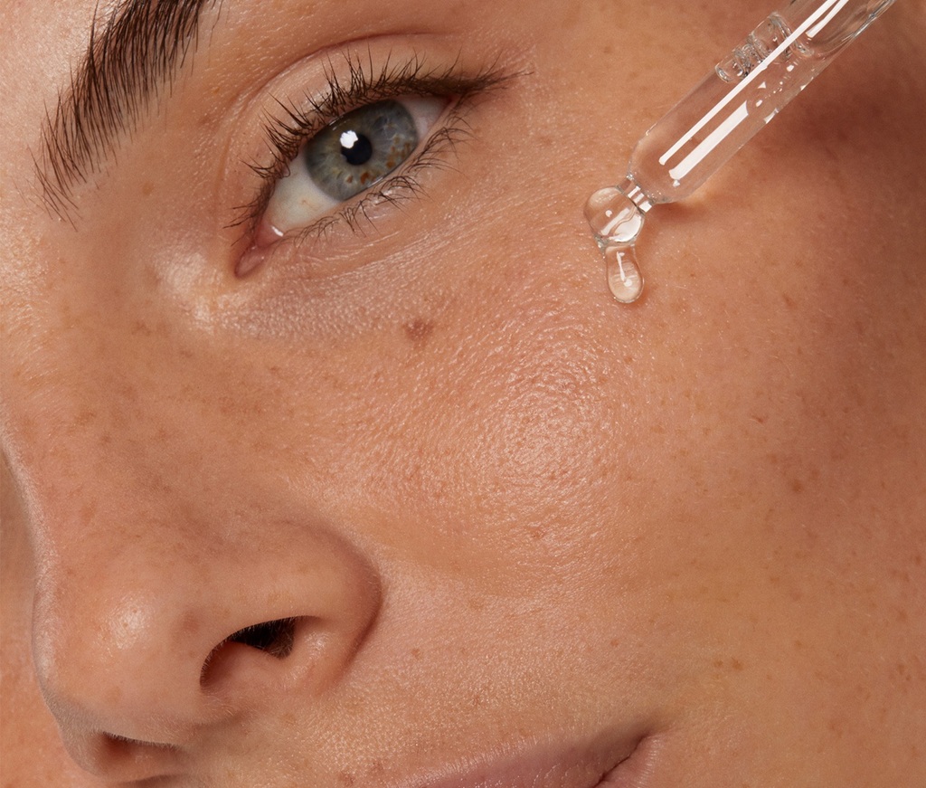 Close up of a woman's face with healthy skin applying NIVEA's New Cellular Serum with a lightweight texture