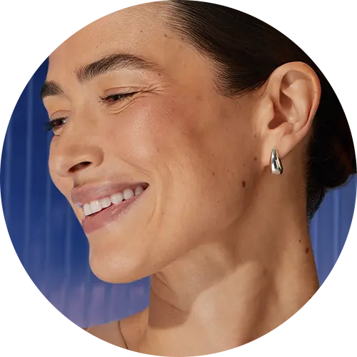 A woman smiles, tilting her head to the side.