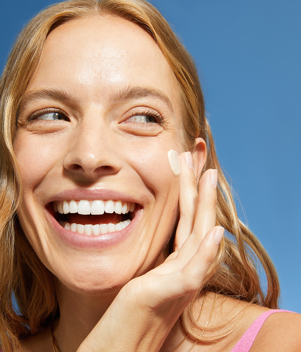 Woman applying NIVEA SUN 2in1 Primer Daily UV Serum with SPF 50+ on face as a primer