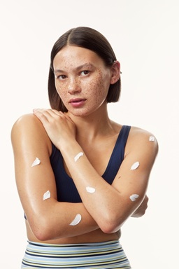 young girl in a top with creams all over her arms