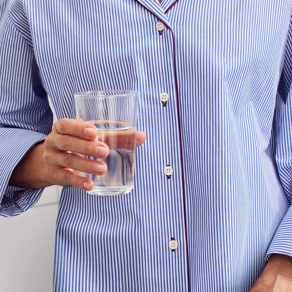 someone with a blue shirt holding a glass of water