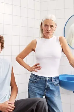 young man and a lady sitting in the bathroom looking to the camera