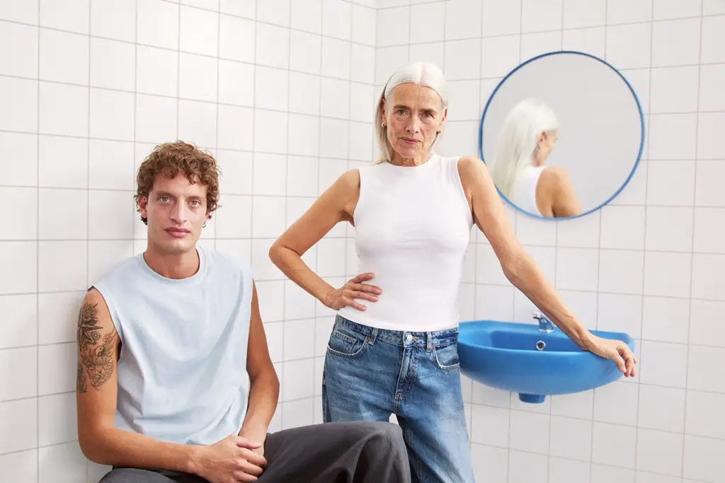 young man and a lady sitting in the bathroom looking to the camera