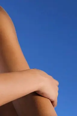 A person sitting in sunlight with dry elbows