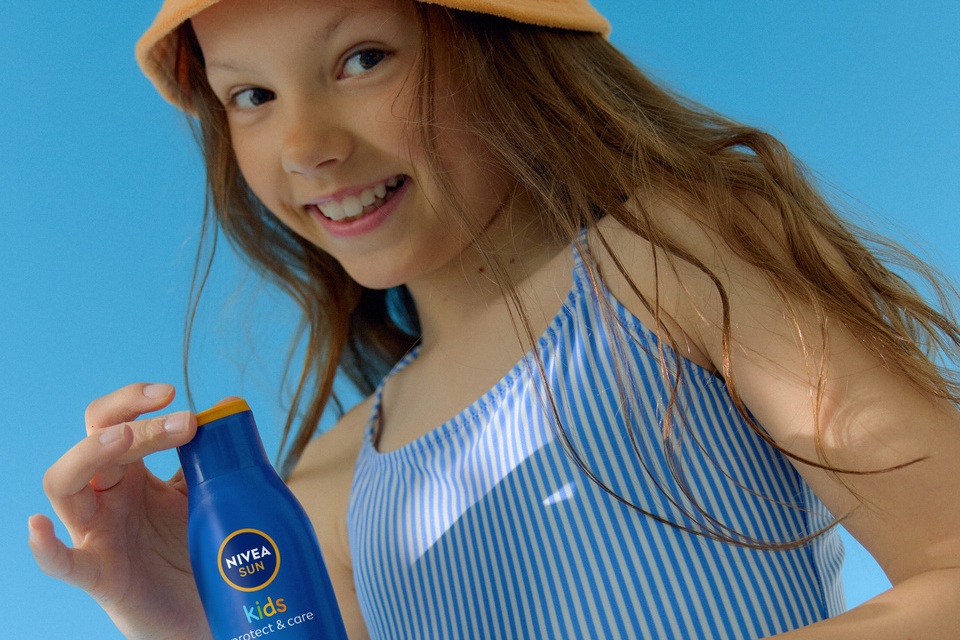 une petite fille utilisant la crème solaire NIVEA Kids Protect & Care SPF 50+