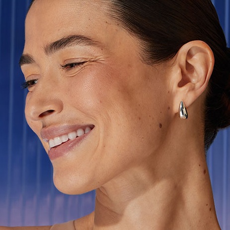 A woman smiles, tilting her head to the side.