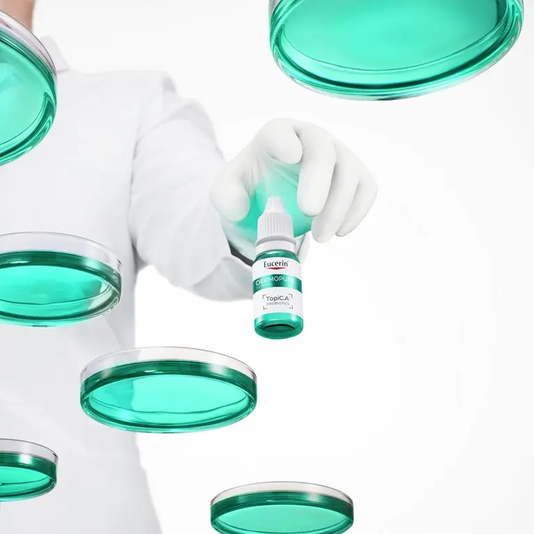 Gloved hand holding a bottle of Eucerin Probiom8 TopiC.A probiotics in a stylised laboratory setting
