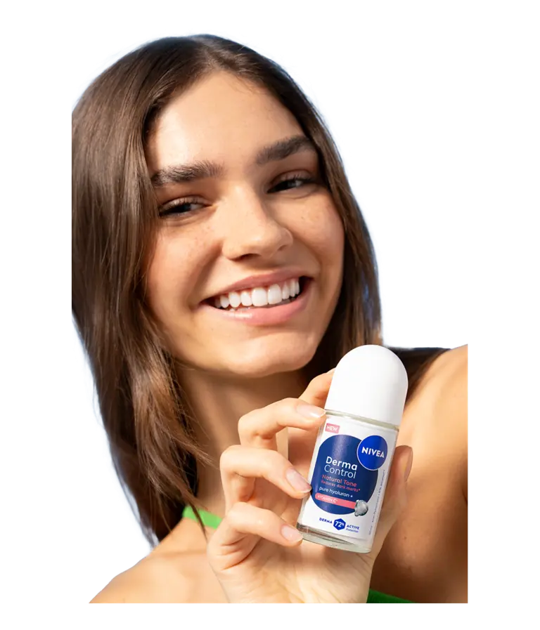 A young smiling woman turns her head while holding up NIVEA Derma Control Natural Tone Deo Roll-On.