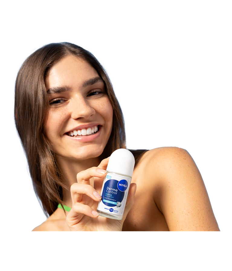 A young smiling woman turns her head while holding up NIVEA Derma Control Defend Deo Roll-On.