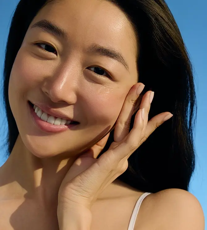 A young woman smiles while swiping on NIVEA SUN Breathable UV Specialist Aqua UV Gel Serum SPF 30.