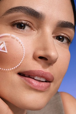 A woman touches her cheekbone area, with a reversing time icon featured over her face.