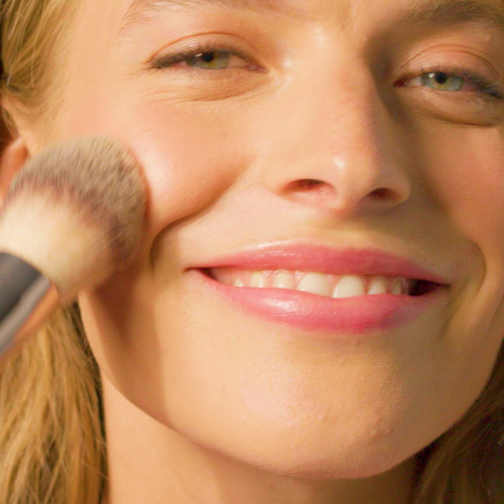 Woman applying thin layer of make up with brush