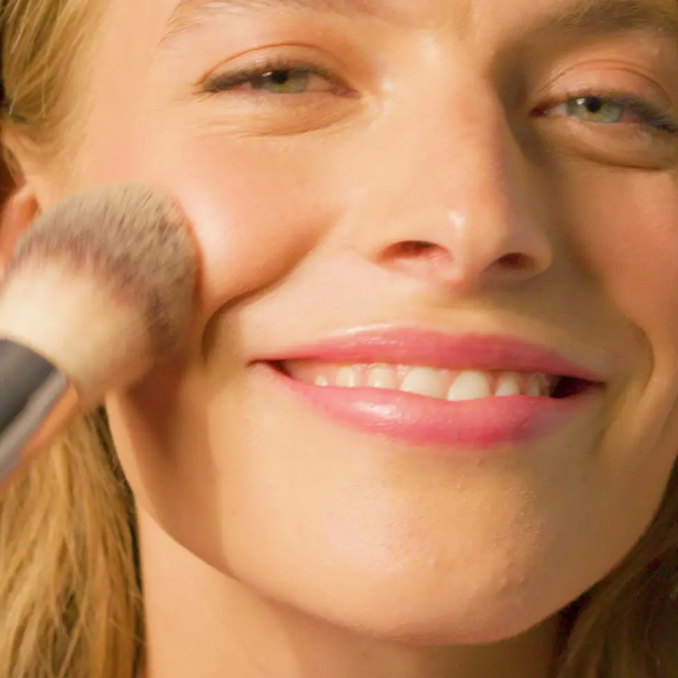 Woman applying thin layer of make up with brush