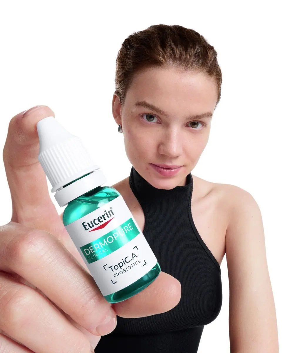Woman holding a bottle of Eucerin Probiom8 TopiC.A probiotics from the Probiom8 routine