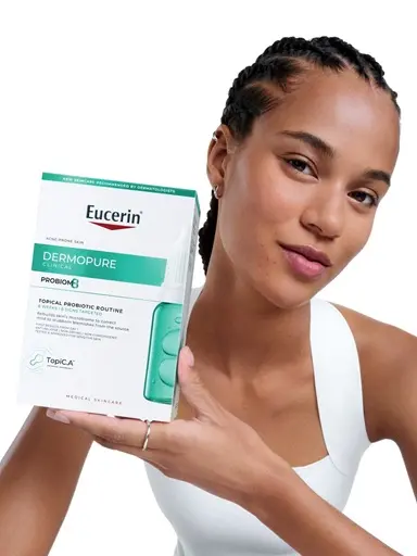 Woman holding up the Eucerin Probiom8 box for acne-prone skin