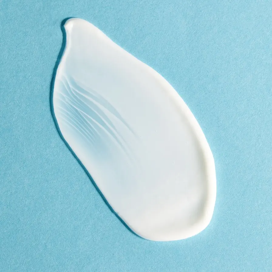 A swipe of Q10 body cream for skin tightening on a blue surface