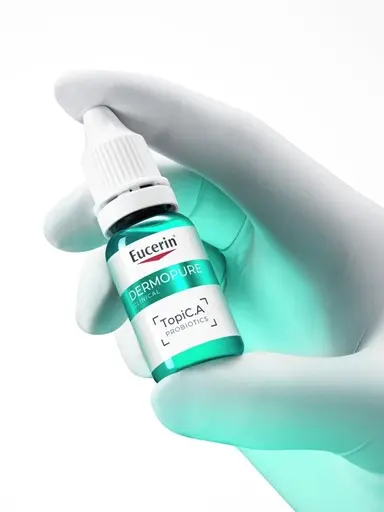 Gloved hand holding a bottle of Eucerin Probiom8 TopiC.A probiotics for acne-prone skin