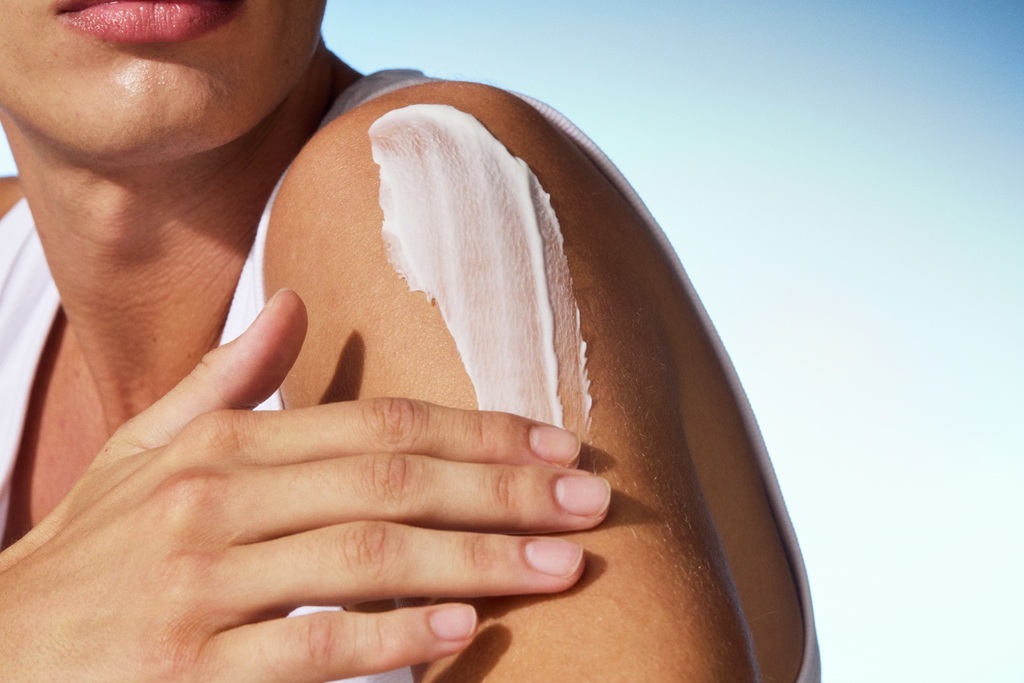 a woman applying lotion to her arm