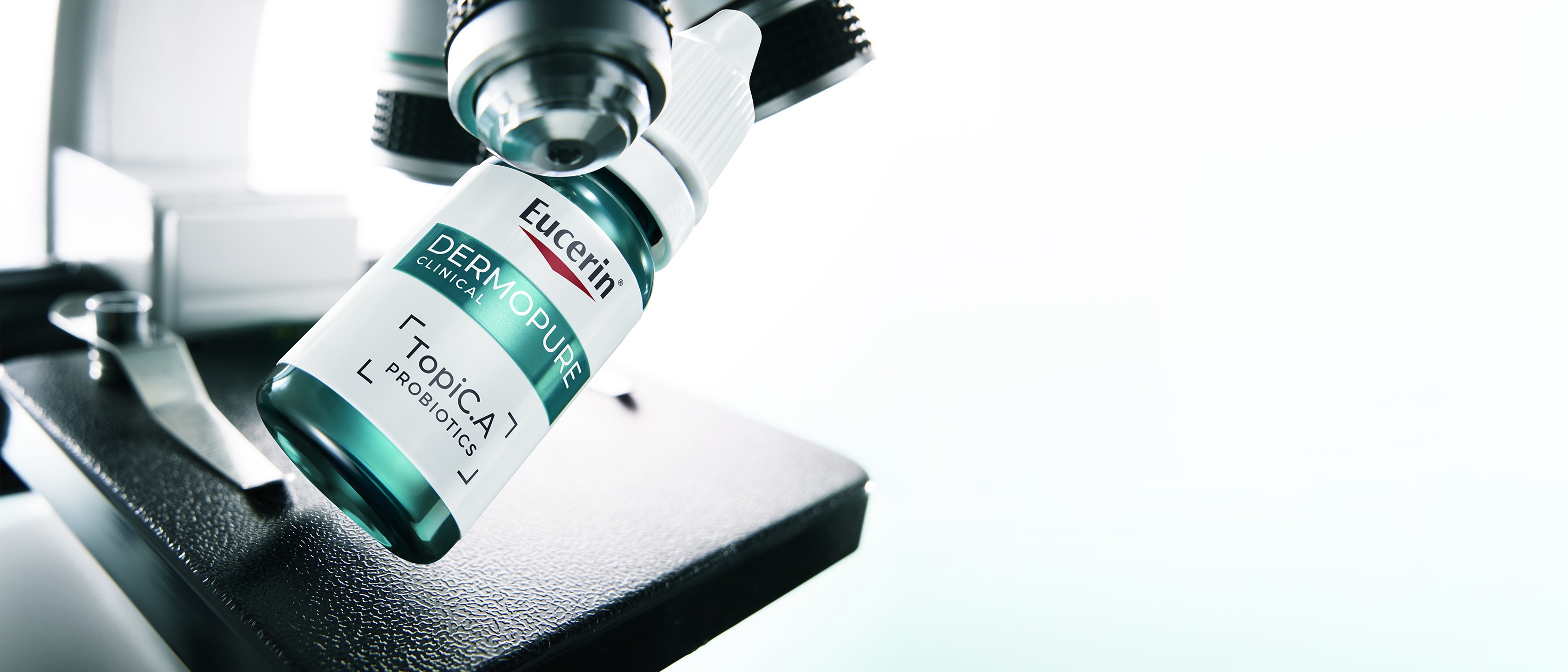 Flasche Eucerin Probiom8 TopiC.A neben einem Mikroskop
