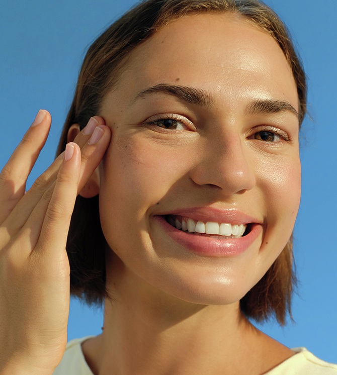 A young woman smiles while swiping on NIVEA SUN Breathable UV Specialist Aqua UV Gel Serum SPF 30.