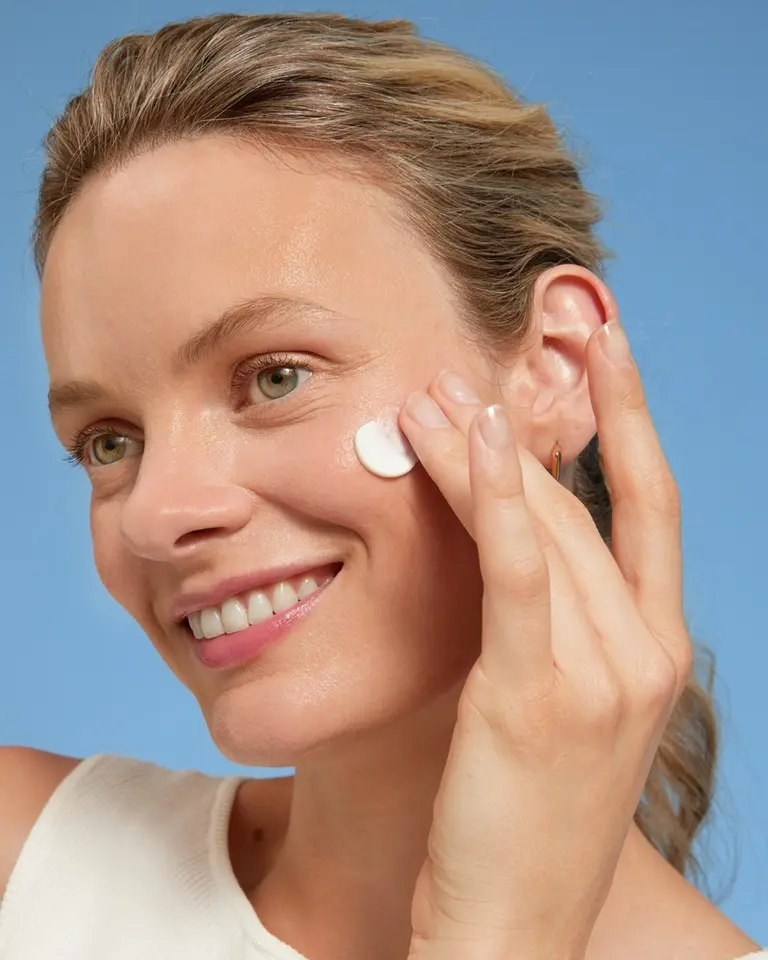 Blond ung kvinna som applicerar Nivea SPF-kräm