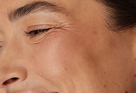 A woman smiles, tilting her head to the side.