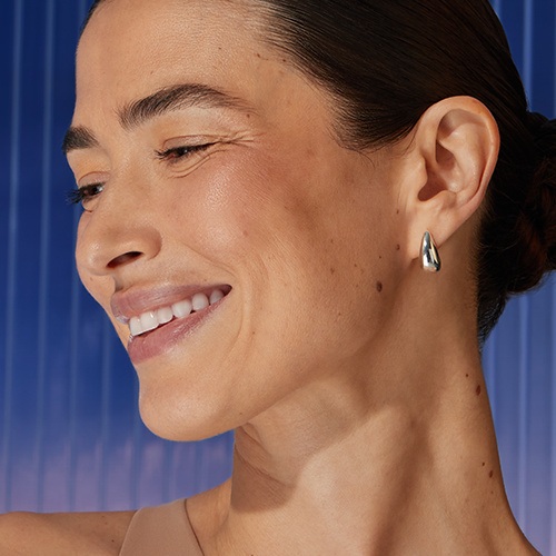 A woman smiles, tilting her head to the side.