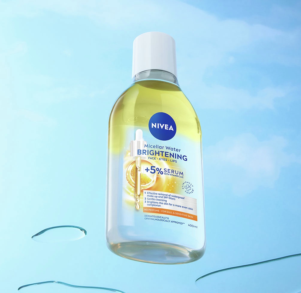 NIVEA Brightening Micellar Water bottle against a sky blue background with floating micellar water